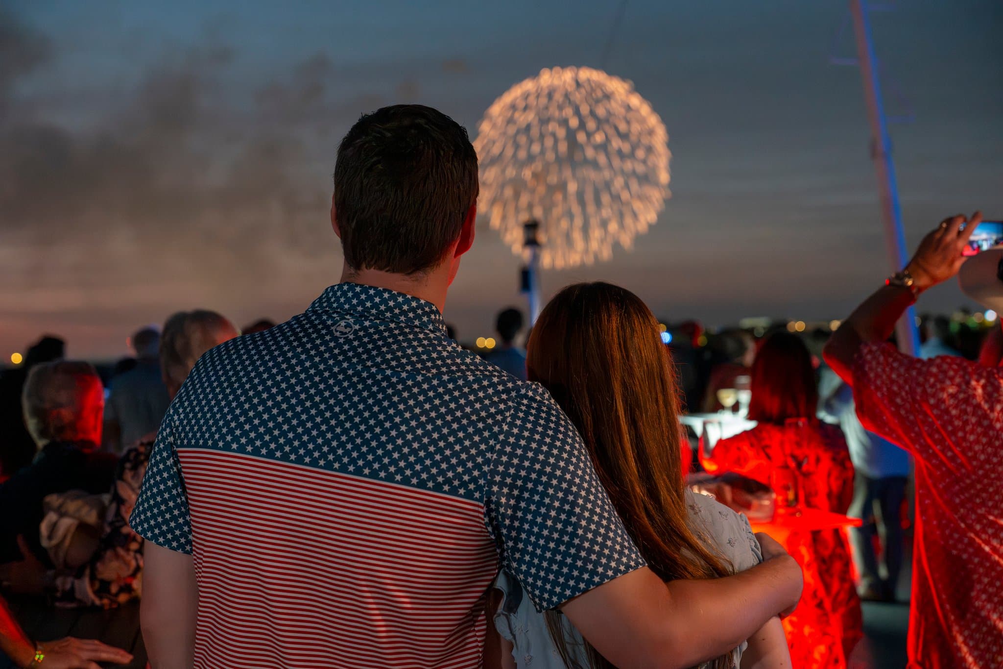 A loving young couple staring out at the fireworks launching over Washington, D.C. on Independence Day, the 4th of July, viewing from a boat on the Potomac River.